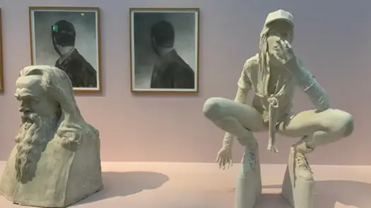 Två skulpturer är placerade framför två målningar, som sitter på en vägg.